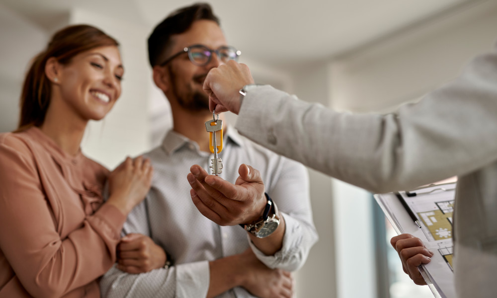 Close-up of real estate agent giving new house keys to a couple.