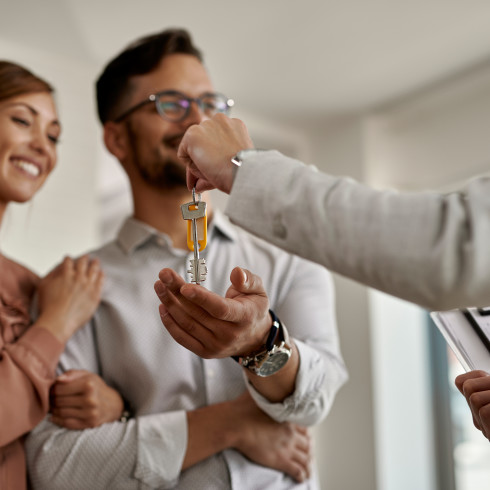 Close-up of real estate agent giving new house keys to a couple.